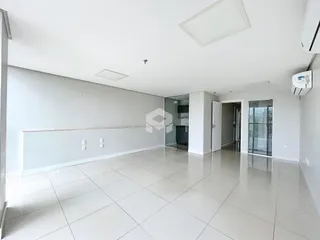 Uma sala de estar ampla com piso claro e paredes brancas.