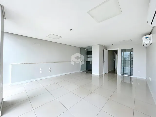 Uma sala de estar ampla com piso claro e paredes brancas.