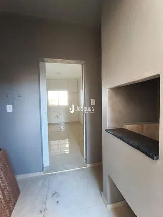 Vista de um corredor interno com portas abertas mostrando uma área de cozinha.