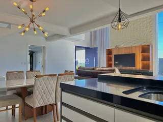 Ambiente moderno de sala de estar e cozinha com iluminação decorativa.