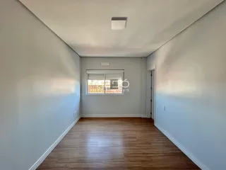 Interior de um ambiente com piso de madeira e paredes claras.