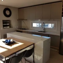 Foto de uma cozinha moderna com bancadas claras e armários brancos.