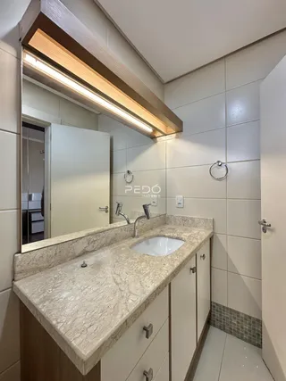 Banheiro com bancada de mármore e revestimento cerâmico.