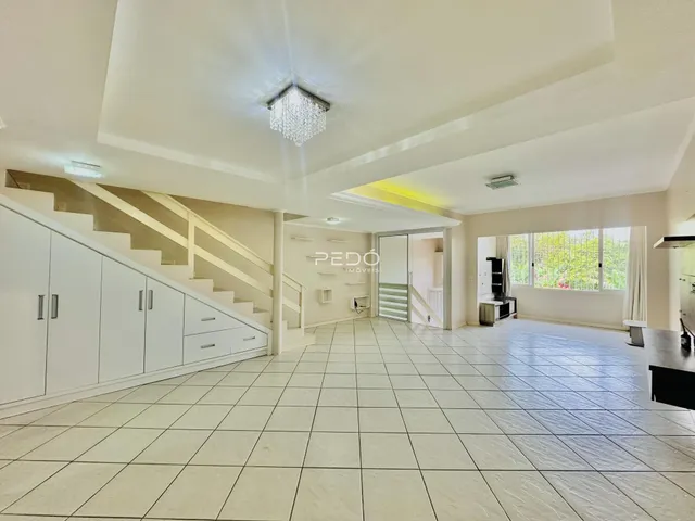 Sala de estar com escadaria e piso de cerâmica clara.