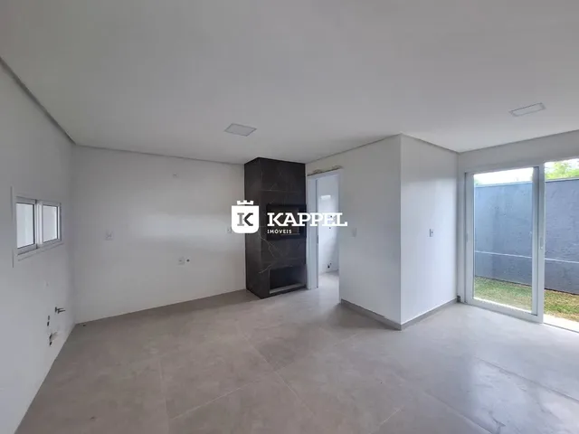 Esta é uma sala ampla e vazia com piso claro e uma parede de destaque em pedra escura.