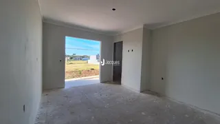 A sala apresenta paredes brancas e um piso de concreto.