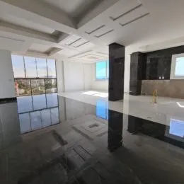 Sala ampla com piso polido e iluminação clara em um imóvel residencial.