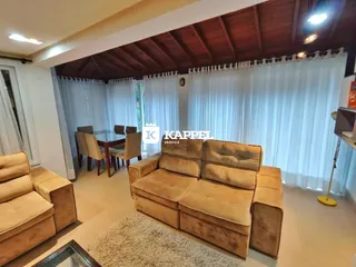 Sala de estar com um sofá grande e cortinas brancas.