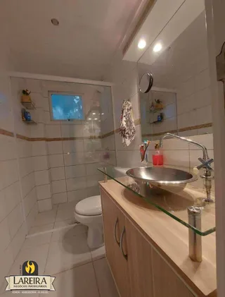 Foto de um banheiro com azulejos brancos e bancada de vidro.