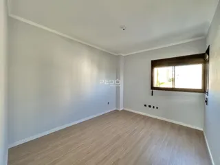 Ambiente interno de uma sala com piso de madeira clara e paredes brancas.
