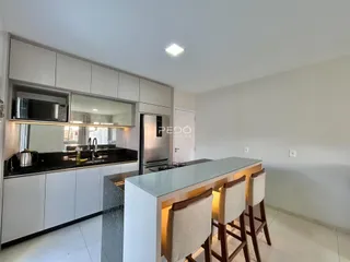 Cozinha moderna com armários brancos e ilha de refeições.