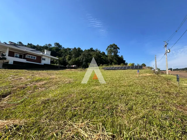 Vista externa de uma propriedade com um campo gramado e vegetação ao fundo.