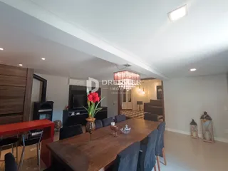 Vista de uma sala de jantar com mesa de madeira no interior de uma residência.