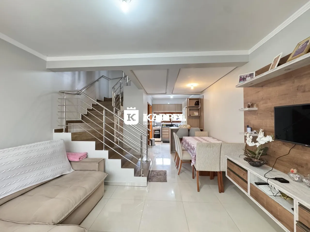Sala de estar com sofá e escadaria moderna em um apartamento.