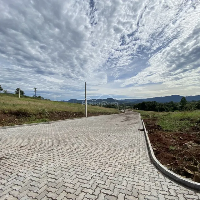 Uma estrada pavimentada curva-se através de uma área gramada com montanhas ao fundo.