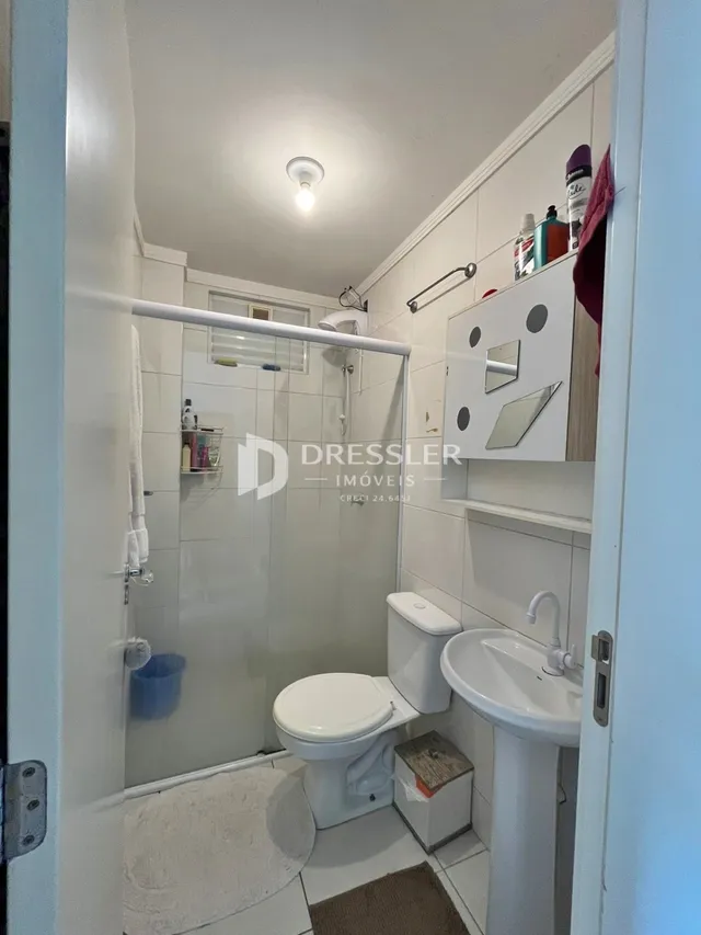 Foto de um banheiro interno com revestimento cerâmico branco.