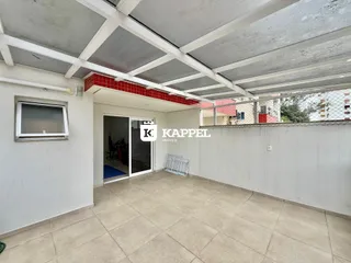 Foto de um pátio coberto com piso de cerâmica e estrutura de concreto.