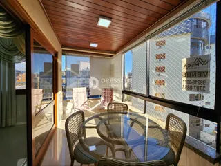 Vista de uma sala de jantar com mesa de vidro e vista para o exterior.