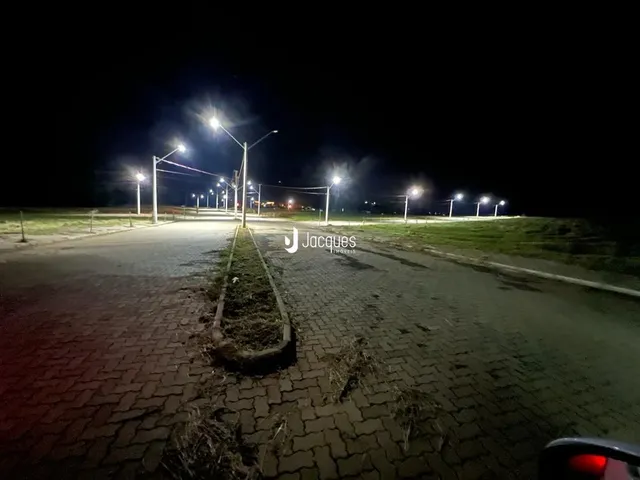 Vista noturna de uma área pavimentada com postes de luz.