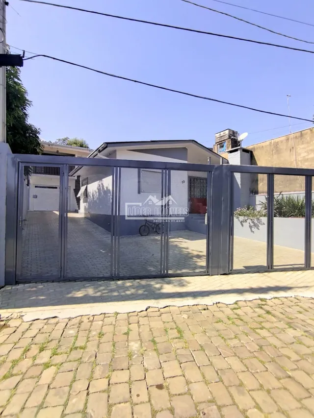 Fachada de uma residência com portão de ferro e piso de tijolos na frente.