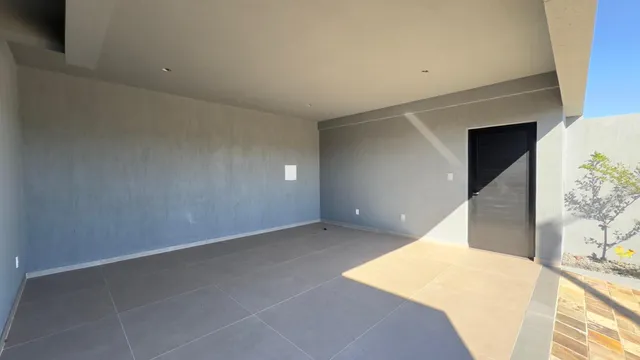 Esta é uma sala ampla e moderna com piso claro e paredes lisas.