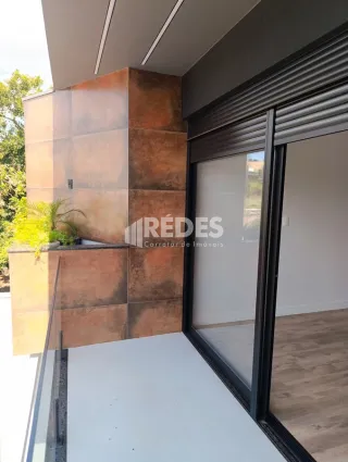 Fachada de um edifício com revestimento de tijolo aparente e grandes portas de vidro.