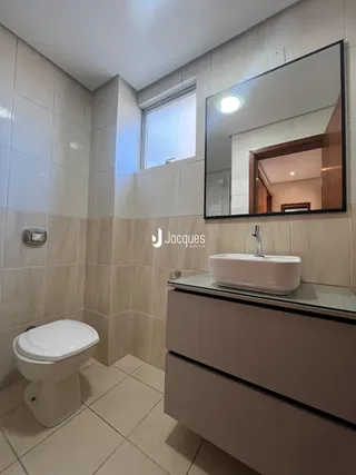 Banheiro com revestimento cerâmico e piso claro.