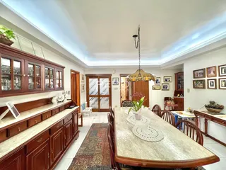 Uma sala de jantar com móveis de madeira escura e piso claro.