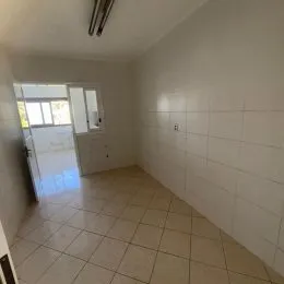 Foto de um corredor interno com piso de cerâmica claro e paredes brancas.