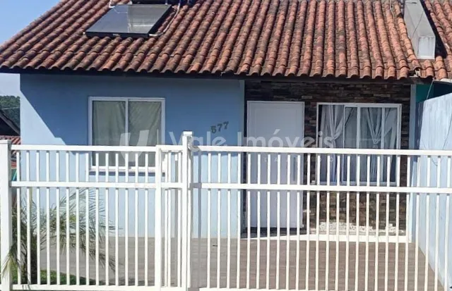 Fachada de uma residência em Lajeado, Brasil, com muro branco e cerca de madeira.