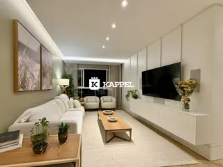 Sala de estar moderna com sofá branco e televisão de tela plana.