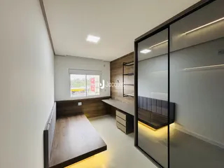 Interior de uma sala com piso de madeira e divisória de vidro.