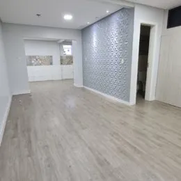 Sala de estar com piso de madeira clara e parede texturizada.
