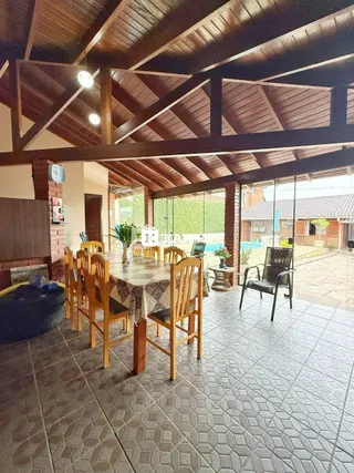 Área externa coberta com mesa de madeira e cadeiras em um pátio.