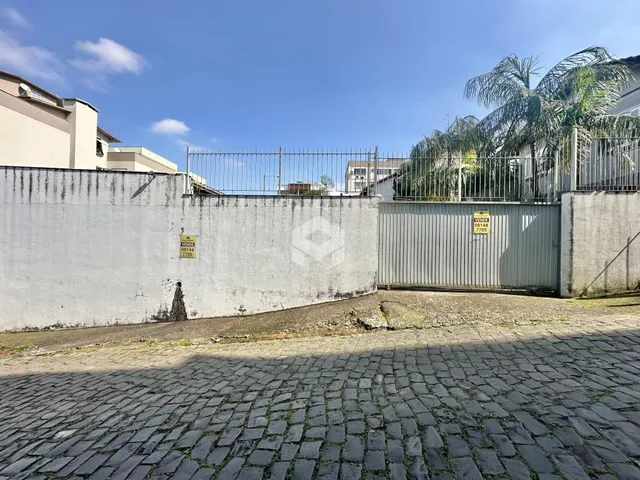 Vista da fachada de uma propriedade com muro e portão de metal.