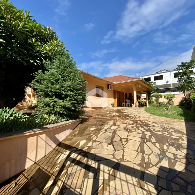 Vista externa de uma propriedade com pátio pavimentado e vegetação exuberante.