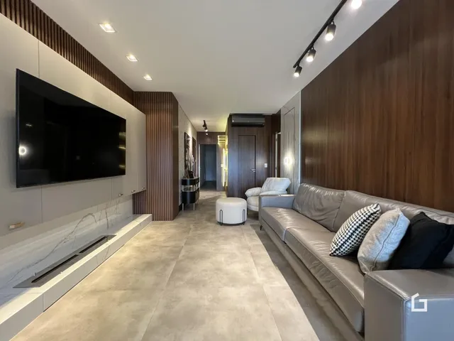 Sala de estar moderna com sofá e televisão em um ambiente com piso claro.