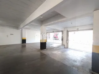 Interior de um espaço com piso de concreto e vigas expostas.