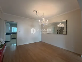 Sala de estar com piso de madeira clara e parede branca.