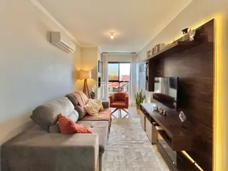 Sala de estar com sofá e rack de TV em um apartamento.