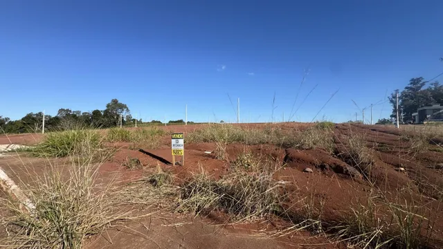 Vista de uma área de terra seca com vegetação rasteira e uma placa de venda em Lajeado.