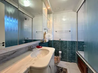 Foto interna de um banheiro com revestimento de azulejos verde-água.