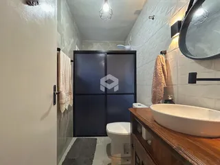 Foto de um banheiro com revestimento de azulejo branco e bancada de madeira.