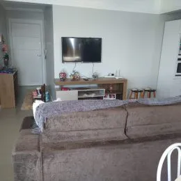 Foto de uma sala de estar com um sofá grande e televisão na parede.