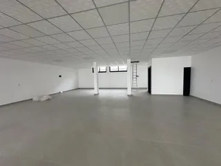 Foto de um ambiente interno amplo e vazio com teto de grid branco.