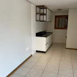 Vista de uma área interna com piso de cerâmica e armários brancos.
