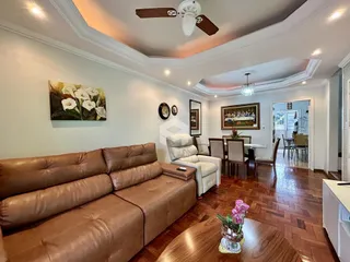 Sala de estar com sofá de couro marrom e piso de madeira em Lajeado.
