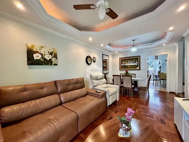 Sala de estar com sofá de couro marrom e piso de madeira em Lajeado.