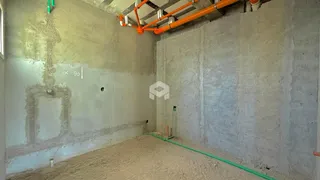 Ambiente interno de uma sala em construção com paredes de concreto aparente.