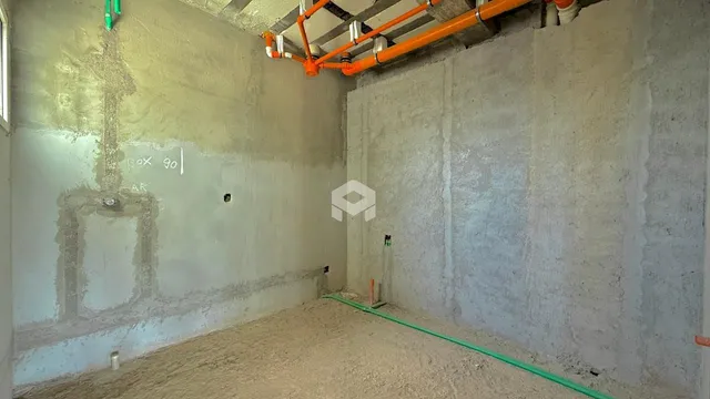 Ambiente interno de uma sala em construção com paredes de concreto aparente.